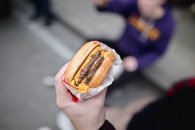 hand holds a fast food double cheeseburger in wrapper