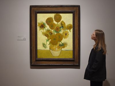 A woman looks at Vincent van Gogh's Sunflowers painting at the EY Exhibition: Van Gogh at Tate Britain in London.